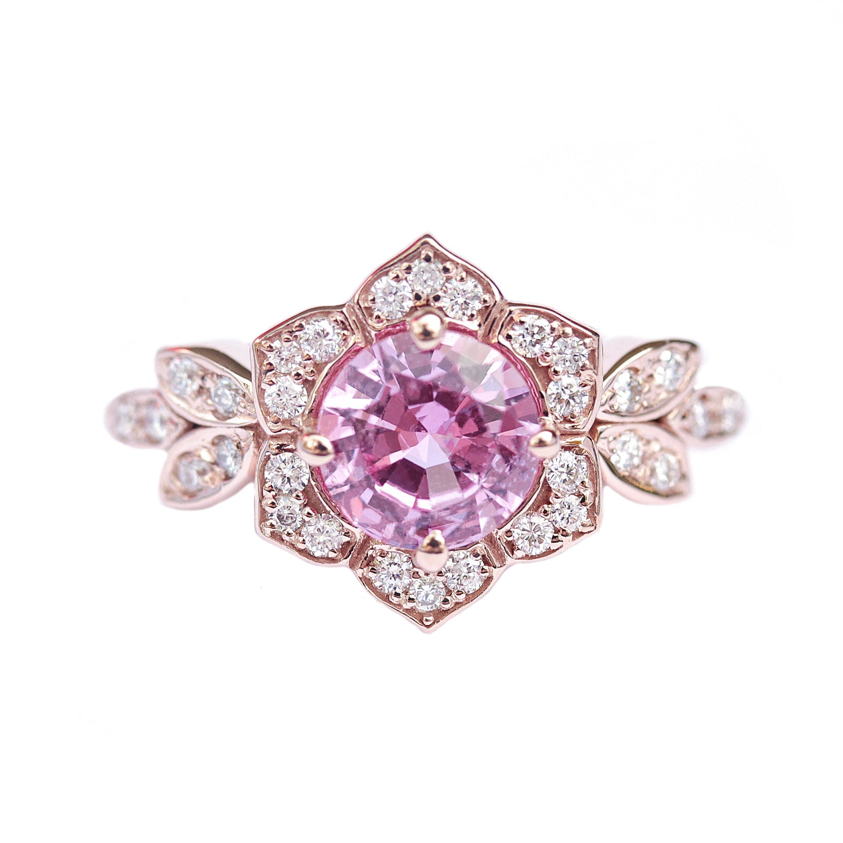 A pink sapphire and diamond engagement ring with a gold band, featuring a central pink sapphire stone surrounded by smaller accent stones.