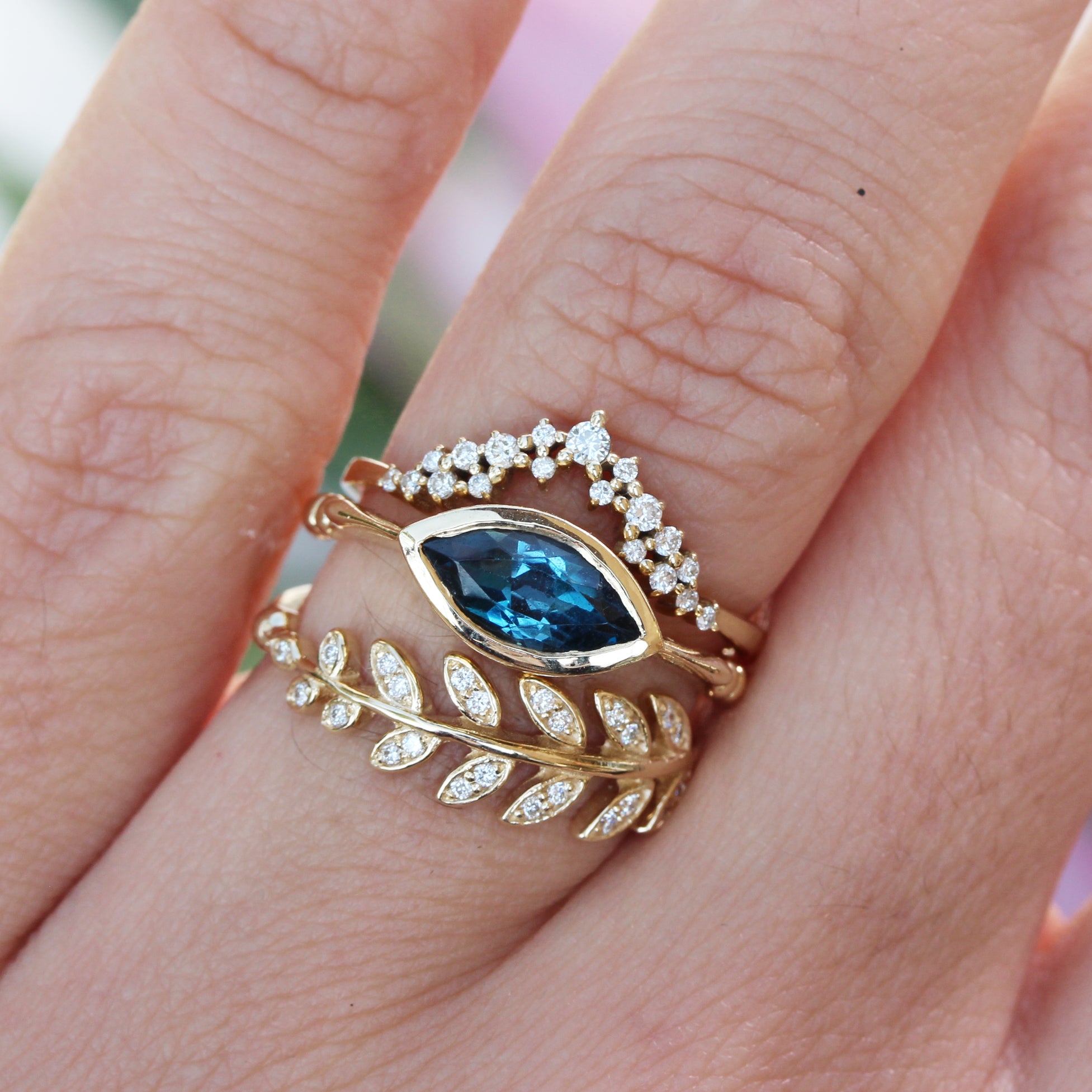 Marquise blue Topaz Solitaire engagement ring, diamond dust nesting ring, olive leaves branch diamond ring, three ring stack on finger in yellow gold