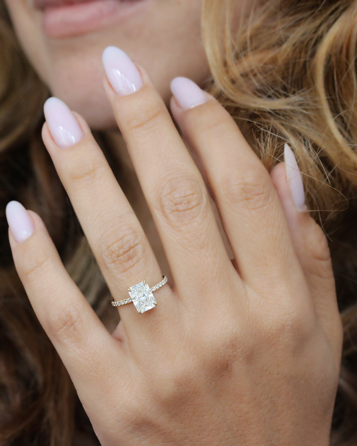 2 ct radiant-cut diamond engagement ring. A yellow gold engagement ring featuring a large rectangular radiant-cut diamond center stone, with a pavé-set diamond band, shown on a clean white background.