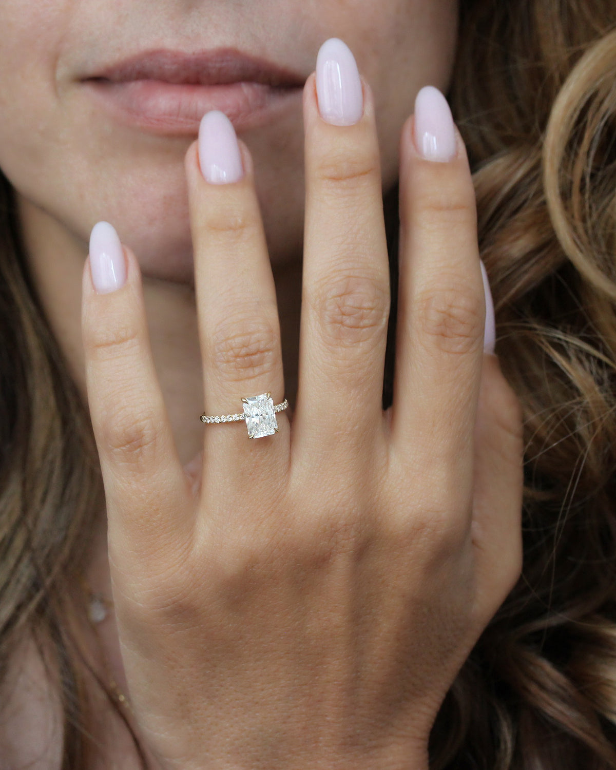 2 ct radiant-cut diamond engagement ring. A yellow gold engagement ring featuring a large rectangular radiant-cut diamond center stone, with a pavé-set diamond band, shown on a clean white background.