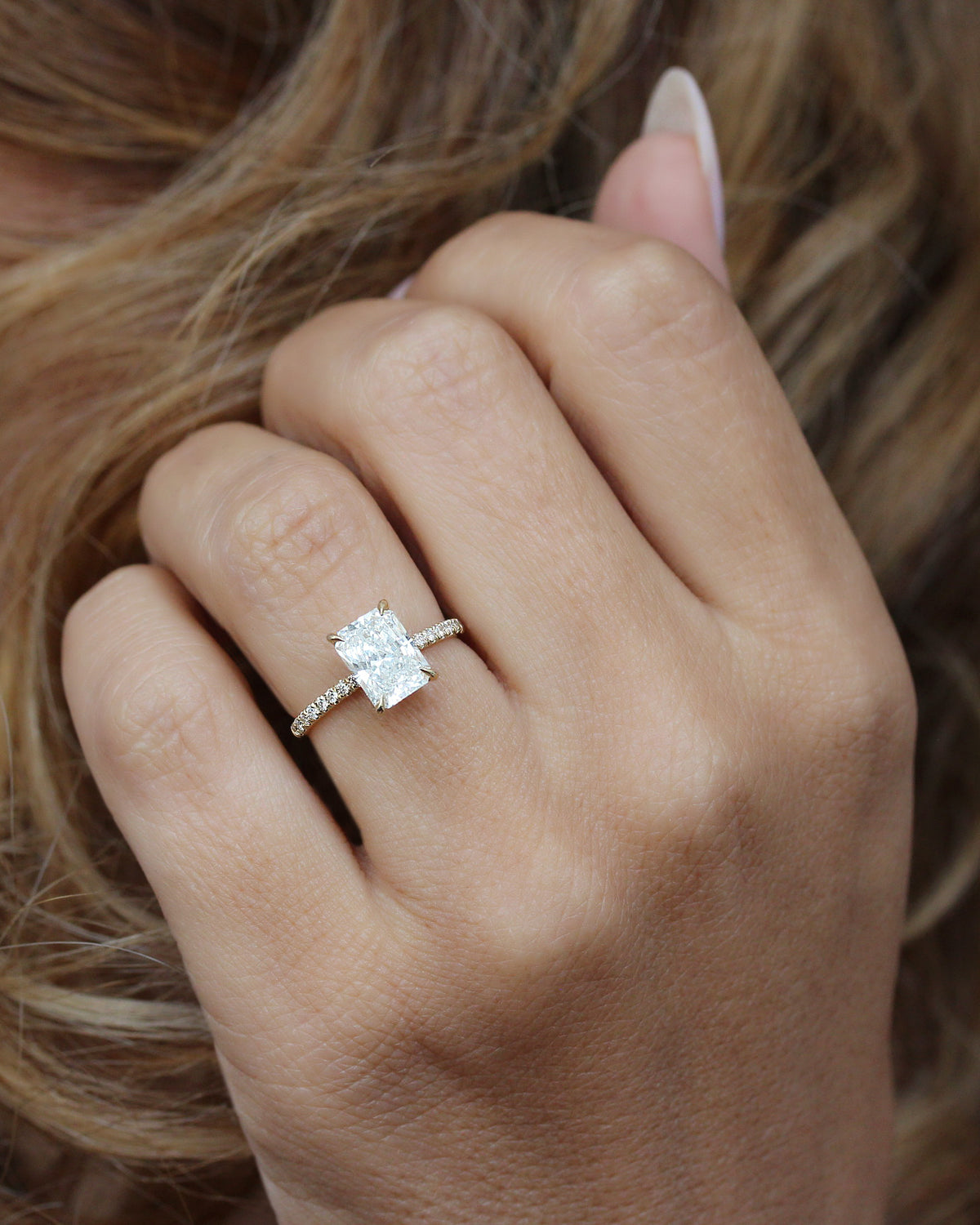 2 ct radiant-cut diamond engagement ring. A yellow gold engagement ring featuring a large rectangular radiant-cut diamond center stone, with a pavé-set diamond band, shown on a clean white background.