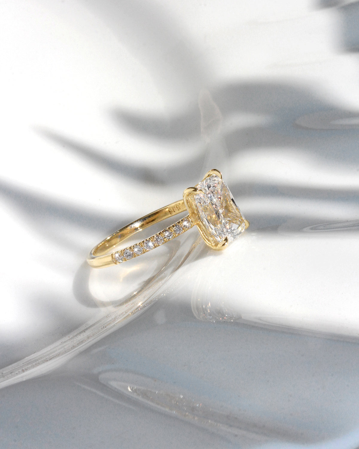 2 ct radiant-cut diamond engagement ring. A yellow gold engagement ring featuring a large rectangular radiant-cut diamond center stone, with a pavé-set diamond band, shown on a clean white background.