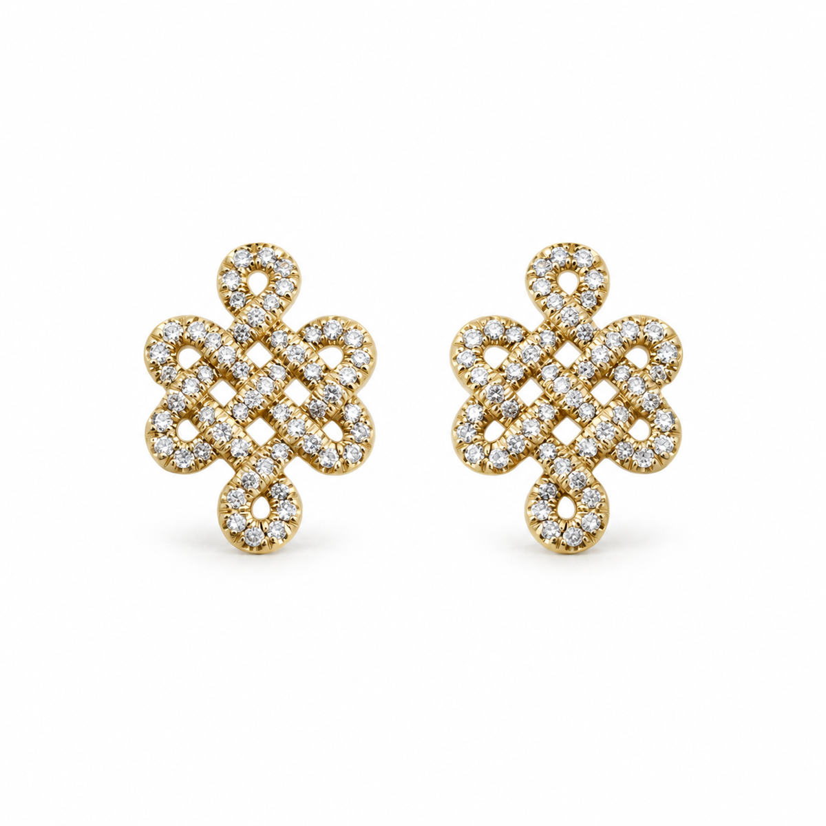 A pair of gold post earrings with an intricate knot design paved with small clear stones, set against a plain white background.