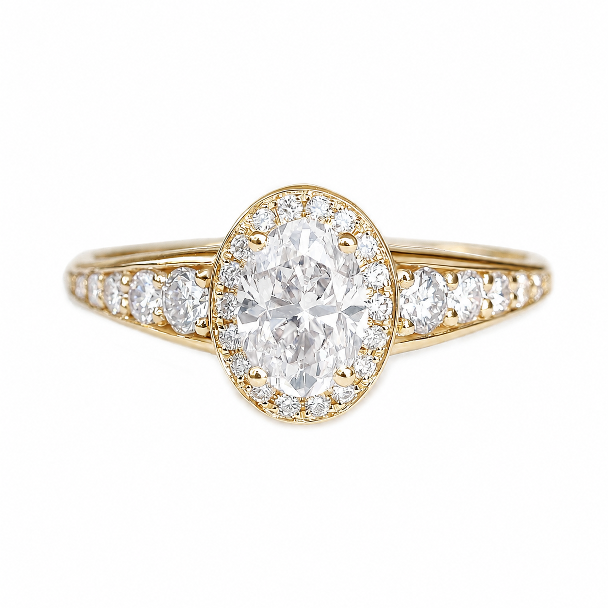 A yellow gold ring featuring an oval-cut diamond center stone surrounded by a halo of smaller round diamonds, with additional diamonds set along the shoulders of the band, shown on a plain white background.