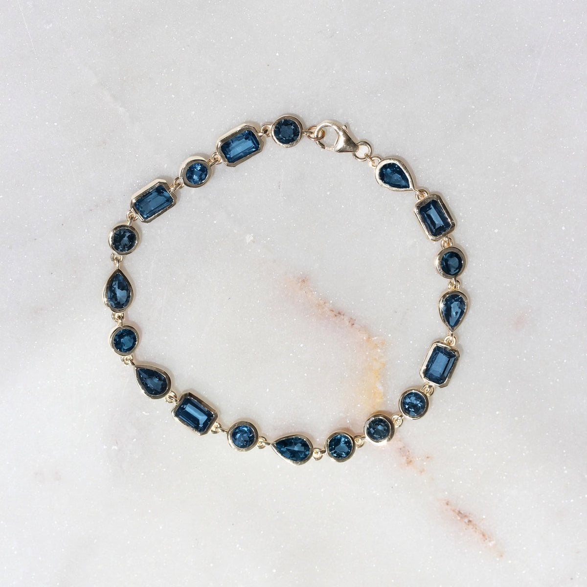 multi shape london blue topaz bezel set bracelet yellow gold