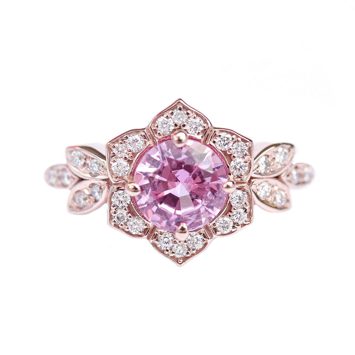 A pink sapphire and diamond engagement ring with a gold band, featuring a central pink sapphire stone surrounded by smaller accent stones.
